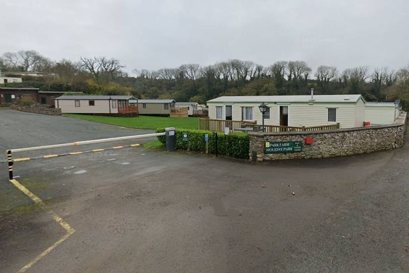 Aerial view of a Welsh holiday park with luxury lodges and cottages surrounded by stunning natural beauty, with a focus on the park's decision to refuse static caravans and its impact on the tourism industry