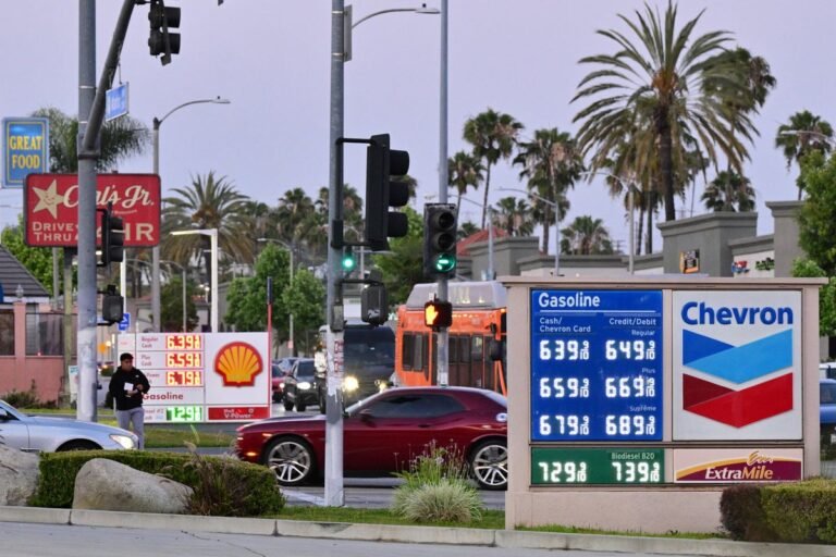 A close-up of a fuel pump with a worried driver in the background, highlighting the primary keyword of petrol prices and the impact on daily life