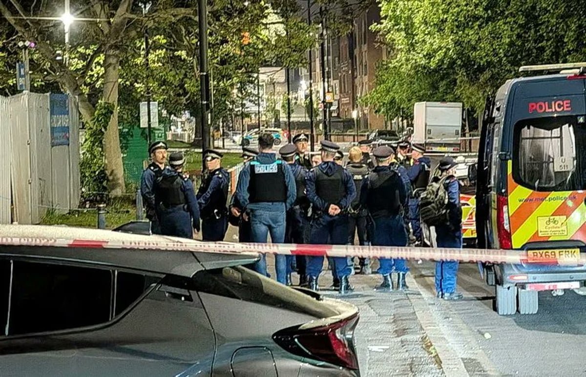 A descriptive image of a south London street, with a police cordon in place following a drive-by shooting at a BBQ, with people gathered nearby, looking concerned and shocked, with the primary keyword 'Brixton shooting' naturally included
