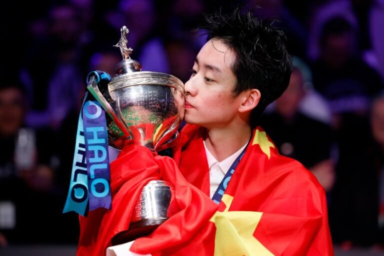 Wu Yize in action at the Crucible, pots the final ball to win the championship, a young Chinese snooker player making history with his incredible performance, the crowd cheers as he celebrates his victory, a moment that will be remembered for years to come, the colour and excitement of the sport brought to life by Wu Yize's talent