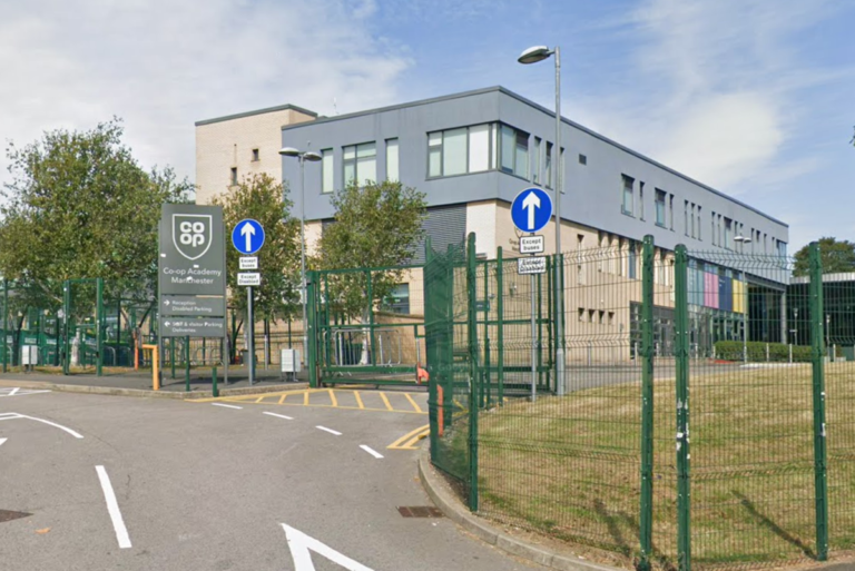A photo of a Manchester school with a police car outside, highlighting the need for increased school safety and support for young people, particularly in the context of the recent stabbing incident