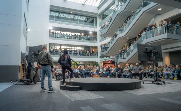 Asha Sharma, Xbox CEO, standing in front of a screen displaying the Xbox logo, with a cityscape in the background, symbolizing the company's evolution and growth in the UK gaming market, with a focus on innovation and expertise
