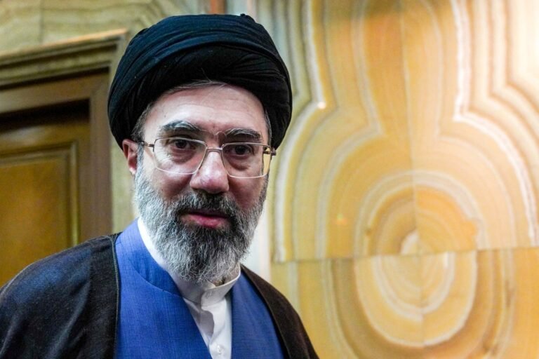 Iran's supreme leader recovering from a scratch behind the ear, with a bandage on their ear, in a meeting with officials, with a natural background, including a Iranian flag, and a colour scheme of red, white, and green, with the primary keyword Iran supreme leader