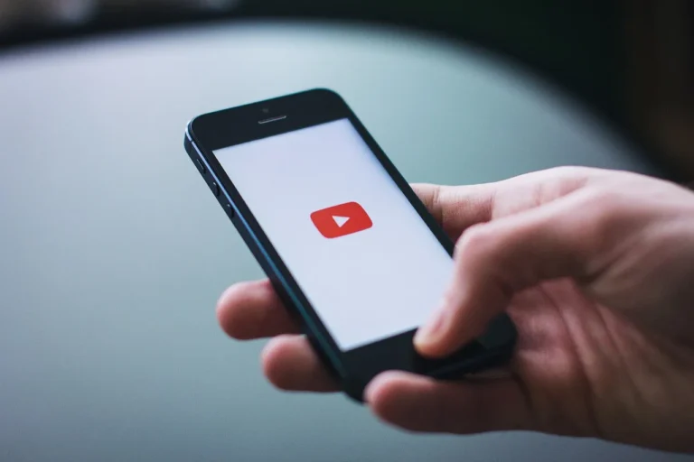 YouTube Premium logo on a mobile device, with a background image of a person listening to music on their phone, highlighting the feature of background playback, which is now exclusive to Premium members