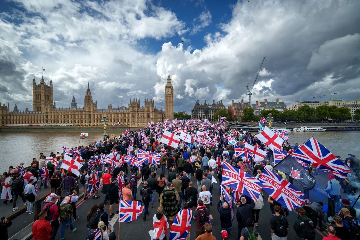 Tommy Robinson leading the Unite the Kingdom march, surrounded by a crowd of protesters and supporters, with a mix of colourful signs and banners, highlighting the event's focus on unity and the primary keyword, Unite the Kingdom