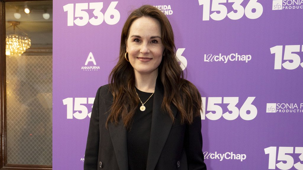 Michelle Dockery, a renowned actress, cradles her newborn baby in her arms, beaming with joy and happiness, as she embarks on her new role as a mother, surrounded by love and warmth, with a gentle smile on her face, and a sparkle in her eyes, as she navigates the challenges of motherhood with courage and resilience.