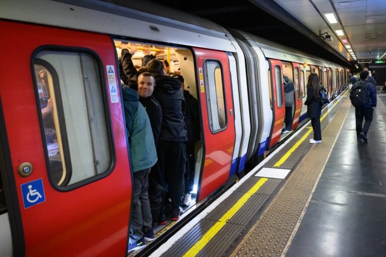 London tube strike: commuters wait at a busy station as union members protest outside, with a sign reading 'fair pay and safe working conditions' in the foreground, highlighting the primary keyword of London tube strikes