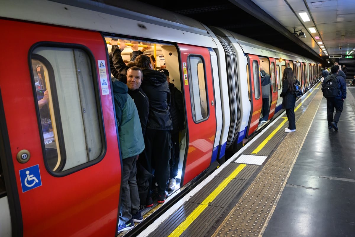 London tube strike: commuters wait at a busy station as union members protest outside, with a sign reading 'fair pay and safe working conditions' in the foreground, highlighting the primary keyword of London tube strikes