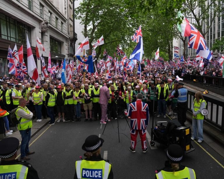 Tommy Robinson addressing a large crowd in London, with a sea of people waving flags and banners, a testament to the power of collective action and the battle for Britain