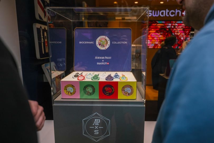 A large crowd of people queuing outside a Swatch store in London, eager to get their hands on the new watch, with a focus on the latest timepiece from the popular brand