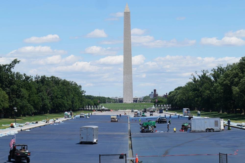 Workers in high-visibility vests and hard hats surrounding the reflecting pool, which is partially filled with blue water, with a union representative in the foreground, highlighting the primary keyword 'worker safety' and the risks associated with the rapid pace of the project
