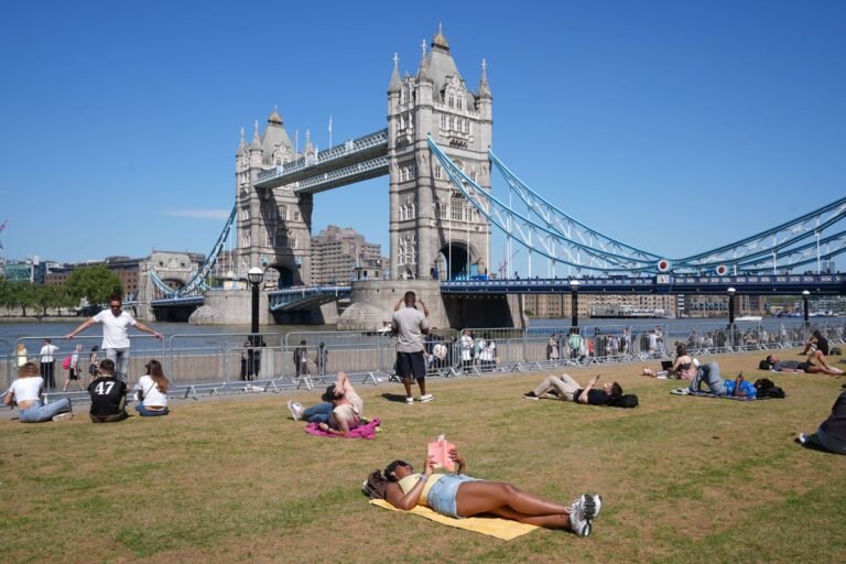 A descriptive image of a sunny day in the UK, with people enjoying the warm weather in a park. The sun is shining, and there are plenty of colourful flowers and trees in bloom. The image captures the beauty of the British countryside on a warm summer's day, with the primary keyword phrase 'UK weather' naturally included