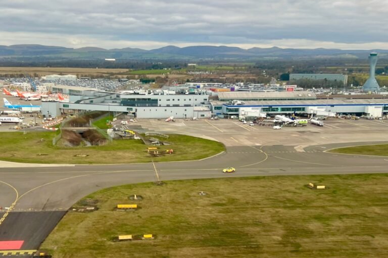A car dropping off passengers at a busy UK airport, with a sign indicating the new drop-off charges, as the UK airport drop-off charges continue to rise, causing concern among travellers