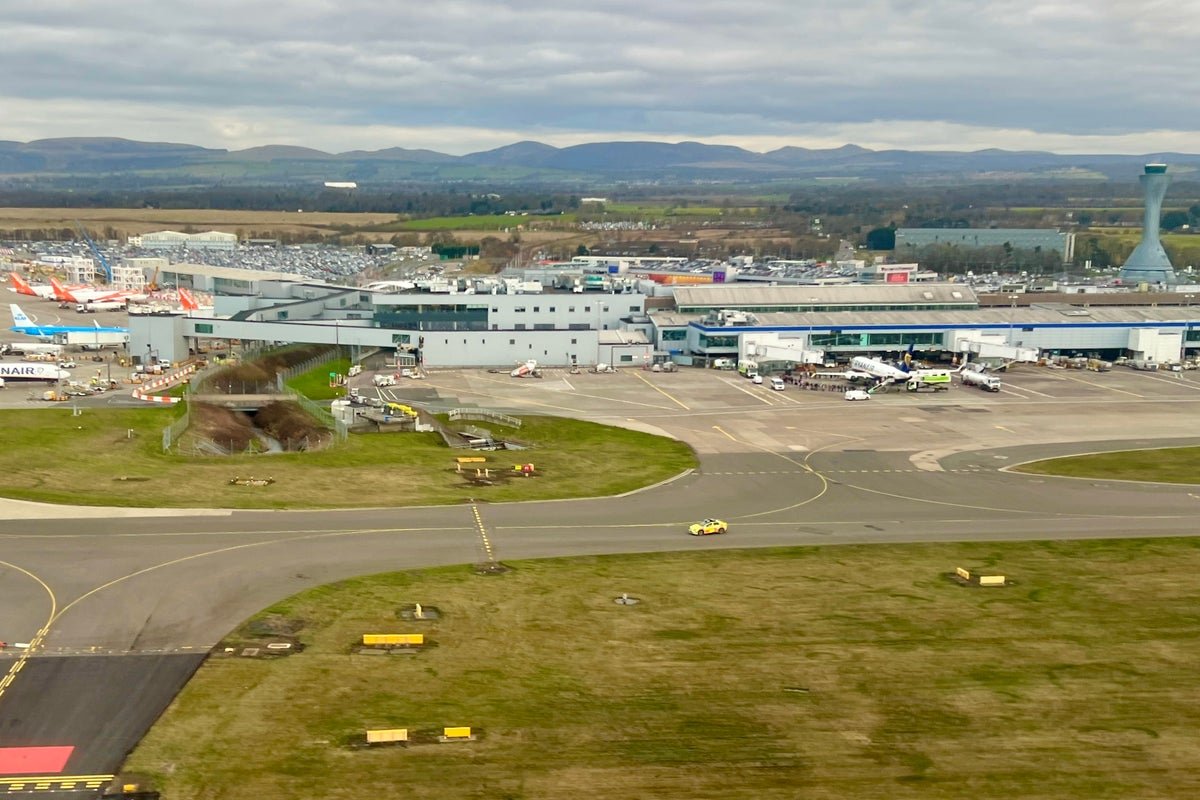 A car dropping off passengers at a busy UK airport, with a sign indicating the new drop-off charges, as the UK airport drop-off charges continue to rise, causing concern among travellers
