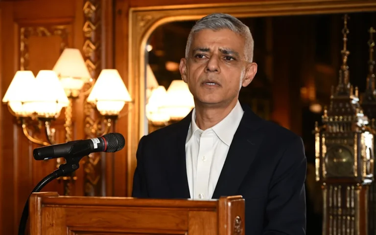 Sadiq Khan, the Mayor of London, speaking about his goal to reverse Brexit and protect the city's economy and global influence, with a background of London's skyline and a union jack flag, symbolising the city's unique position as a global hub
