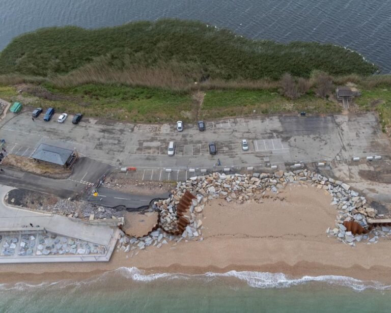 A dramatic image of a UK coastline, with waves crashing against the shore and a railway line in the background, highlighting the impact of rising sea levels on our transport infrastructure and the need for effective sea defences to protect our communities
