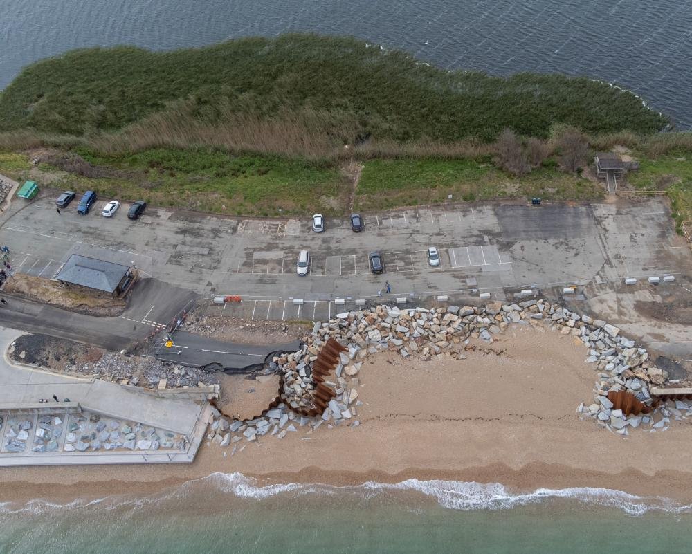 A dramatic image of a UK coastline, with waves crashing against the shore and a railway line in the background, highlighting the impact of rising sea levels on our transport infrastructure and the need for effective sea defences to protect our communities