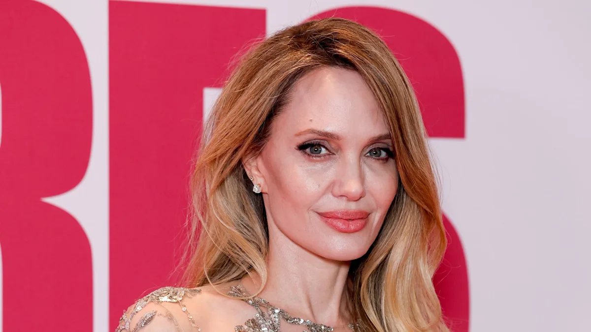 Angelina Jolie wearing a daring 'naked' dress on the red carpet, posing for photographs with confidence and poise, showcasing her latest fashion statement and cementing her status as a style icon