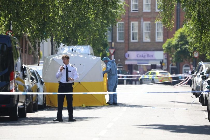 A floral tribute near the scene of the fatal stabbing in Kilburn, with a photo of the victim and messages of condolence from the community, highlighting the devastating impact of knife crime on families and communities