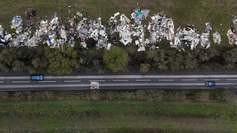 A farmer stands amidst a pile of dumped waste on his land, highlighting the devastating impact of fly-tipping on rural communities and the environment, with a focus on the primary keyword fly-tipping