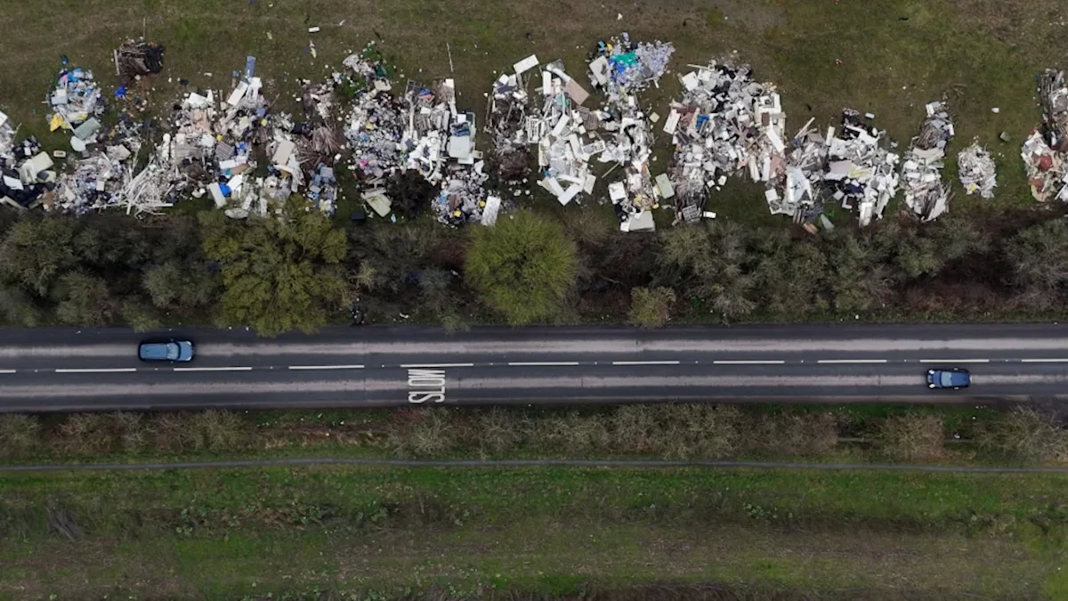 A farmer stands amidst a pile of dumped waste on his land, highlighting the devastating impact of fly-tipping on rural communities and the environment, with a focus on the primary keyword fly-tipping