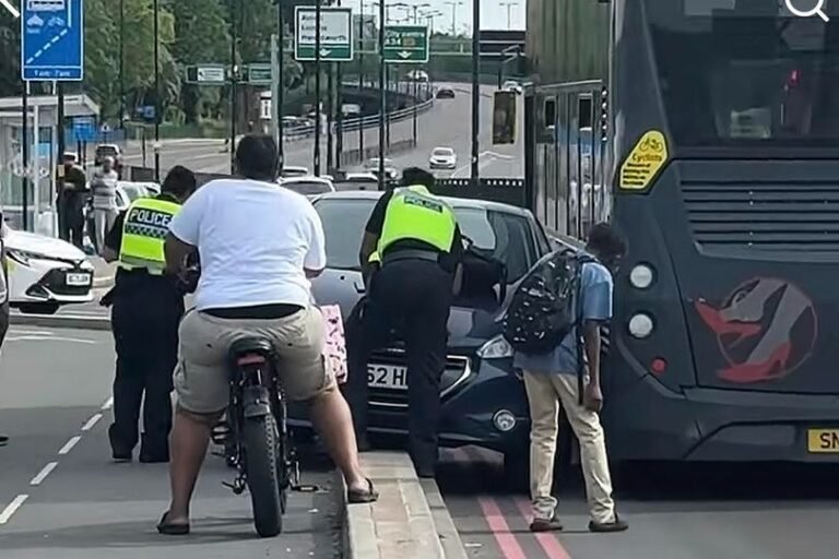 A car trapped beside a bus on a busy Birmingham route, with people gathered around, trying to make sense of the situation, the primary keyword being 'Birmingham bus route'