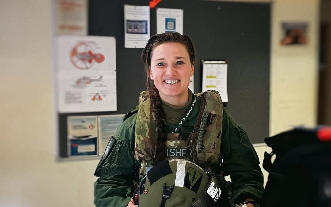 A photo of a female commando in uniform, with a helicopter in the background, the primary keyword 'female commando' is used to describe the image, the colour of the uniform is a deep blue and the helicopter is a sleek black, the image is a poignant reminder of the sacrifices made by soldiers