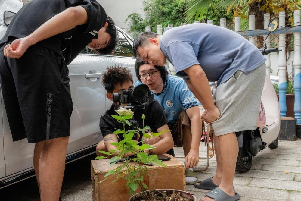 A group of young Chinese filmmakers gathered around a camera, discussing their latest project and how to navigate the complex censorship rules in China, with a focus on independent cinema and creative freedom