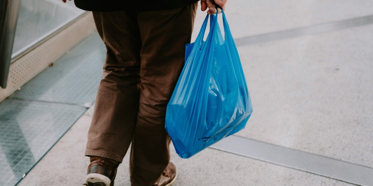 A person holding a reusable shopping bag, with a background of plastic bags and recycling symbols, highlighting the importance of sustainable behaviour and responsible waste disposal