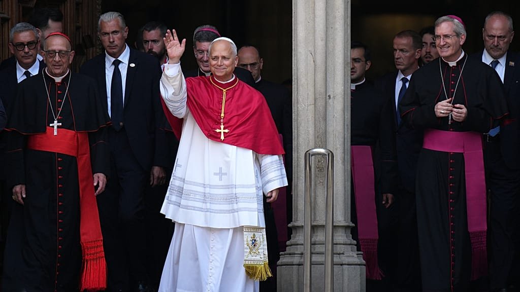 Pope Leo XIV waves to crowds in Barcelona, surrounded by Catholic dignitaries and devotees, as he begins his historic visit to the city, spreading a message of love and compassion to the Catholic community in Spain.