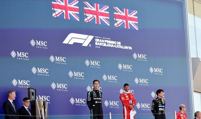 The all-British podium at the Barcelona-Catalunya Grand Prix, featuring Hamilton, Russell, and Norris, celebrating their remarkable achievement in the world of Formula 1, with a sea of British flags waving in the background, capturing the colour and atmosphere of the event