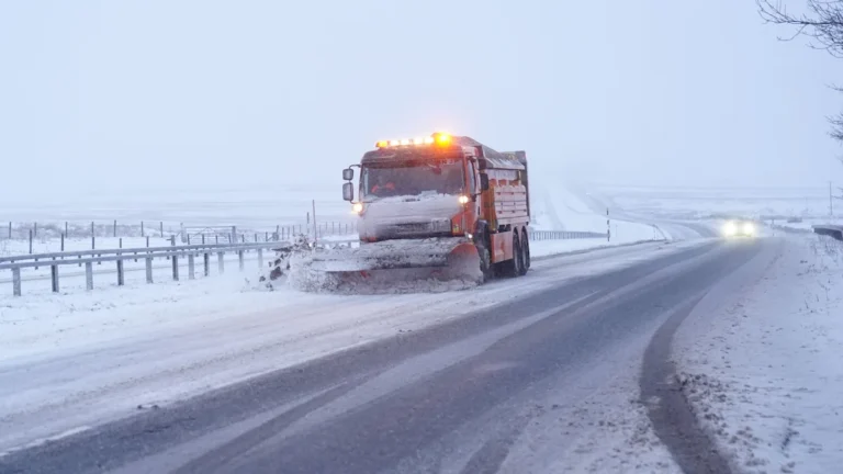 Flooding in the UK, with snow-covered trees and a river bursting its banks, highlighting the severe weather warning in place