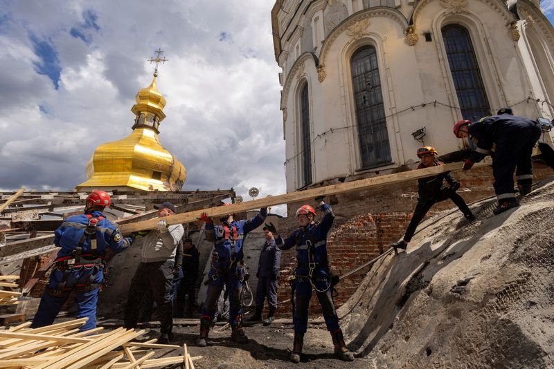 A historic monastery in Kyiv, Ukraine, with a stunning colourful facade and intricate stone carvings, undergoing restoration work after suffering significant damage, with a focus on preserving its cultural significance and historical importance