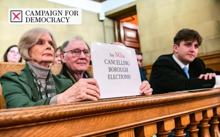 Labour leader Keir Starmer speaking at a podium, with a background of Labour party flags and a cityscape, symbolising the party's commitment to local democracy and electoral process