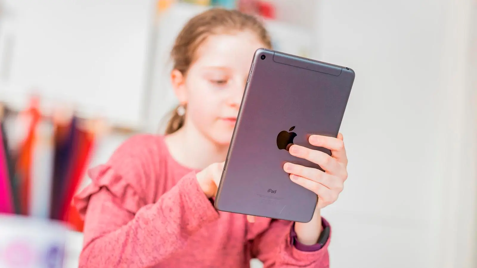 A young girl using a tablet with a concerned expression, highlighting the need for online child safety measures to protect children from harmful content, including explicit AI-generated images