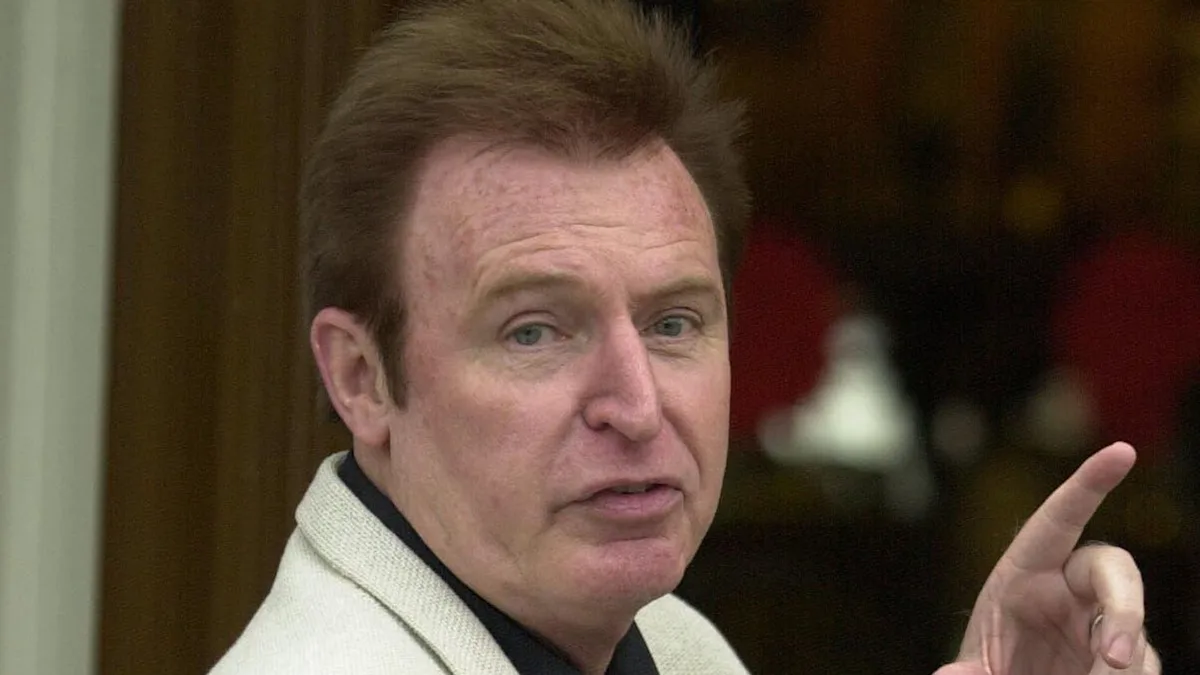 A photograph of Mike McCartney, Paul McCartney's brother, with a guitar and camera, showcasing his passion for music and photography, with a subtle colour palette and muted tones, highlighting his creative behaviour and artistic skills